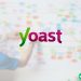 A man mapping out his website on a white board with post-it notes. The Yoast SEO plugin logo is overlaid on top of the image.