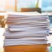 A massive stack of resumes sitting on a desk, waiting to be sifted through.