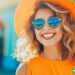 A woman with a bright outfit and sunglasses on with a big smile on her face.