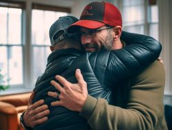 A father hugging his adult son in the living room.
