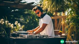 A man working a DJ booth at an outdoor venue as a side hustle.